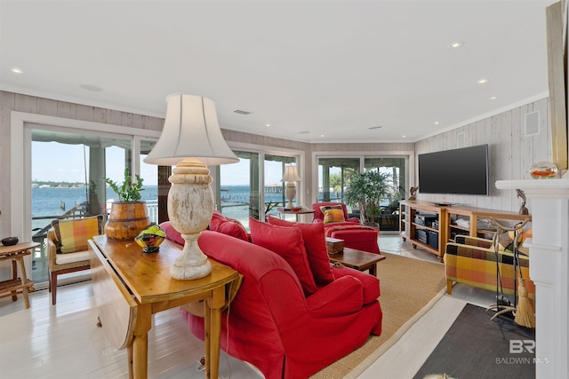 living room with plenty of natural light, crown molding, a water view, and light wood-type flooring