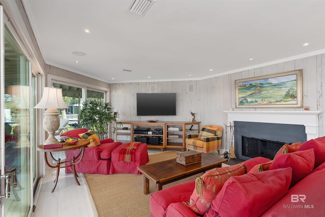 living room with ornamental molding, wooden walls, and light wood-type flooring