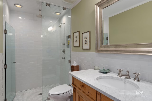 bathroom featuring tile walls, vanity, a shower with shower door, and toilet