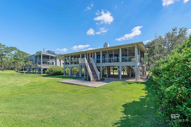 rear view of property with a lawn and a sunroom