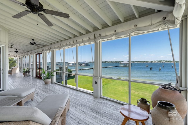 unfurnished sunroom featuring a water view, lofted ceiling with beams, and a wealth of natural light