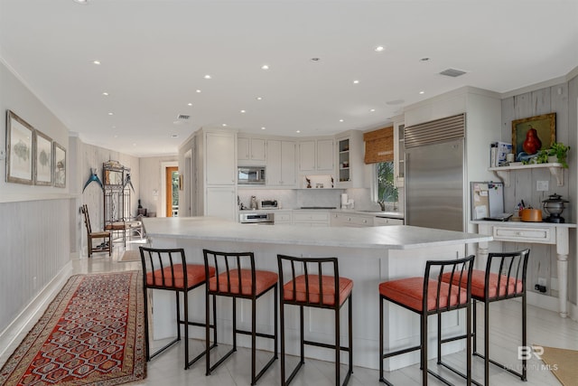 kitchen with a large island, built in appliances, and white cabinetry