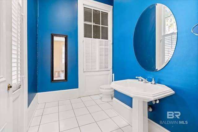 bathroom with a healthy amount of sunlight, toilet, and tile patterned flooring