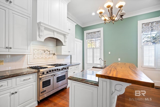 kitchen featuring sink, butcher block countertops, a center island with sink, double oven range, and white cabinets