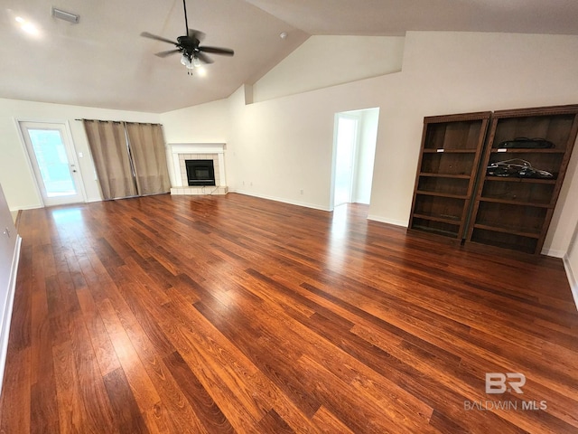 unfurnished living room with a fireplace, vaulted ceiling, ceiling fan, and dark wood-type flooring