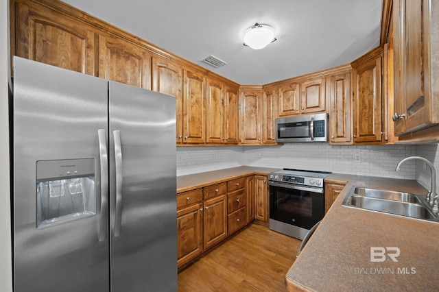 602 W 4th St, Bay Minette, AL 36507 - kitchen with appliances with stainless steel finishes, a sink, tasteful backsplash, and light wood-type flooring
