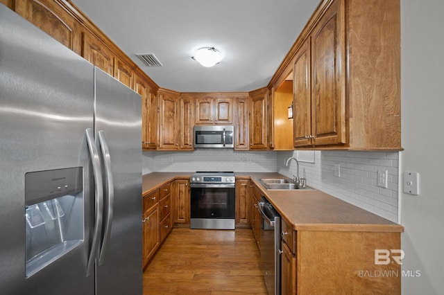 602 W 4th St, Bay Minette, AL 36507 - kitchen featuring appliances with stainless steel finishes, a sink, wood finished floors, and brown cabinetry