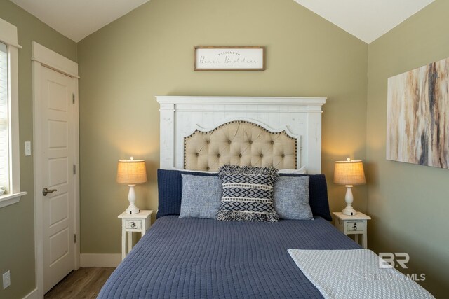 bedroom featuring lofted ceiling, baseboards, and wood finished floors