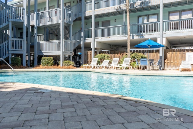 community pool with a patio area and fence