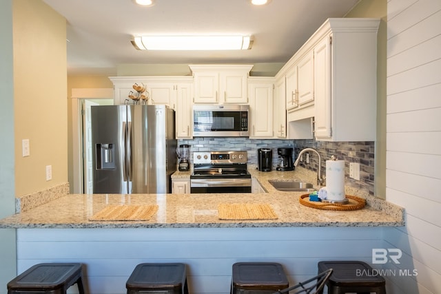 kitchen featuring a peninsula, appliances with stainless steel finishes, a sink, and decorative backsplash