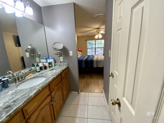 bathroom with tile patterned flooring, vanity, a textured ceiling, and ceiling fan with notable chandelier