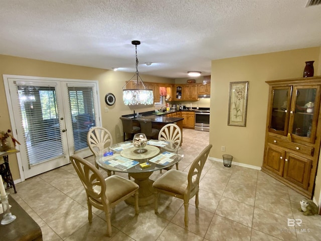 dining area with french doors, light tile patterned flooring, and a textured ceiling