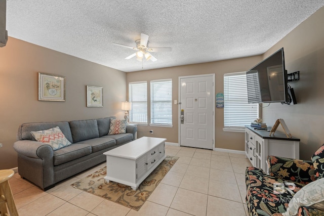 living room with ceiling fan, a textured ceiling, and light tile patterned flooring