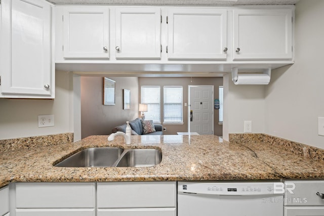 kitchen with light stone counters, white cabinets, dishwasher, and sink