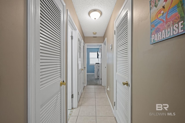 hall featuring a textured ceiling and light tile patterned floors