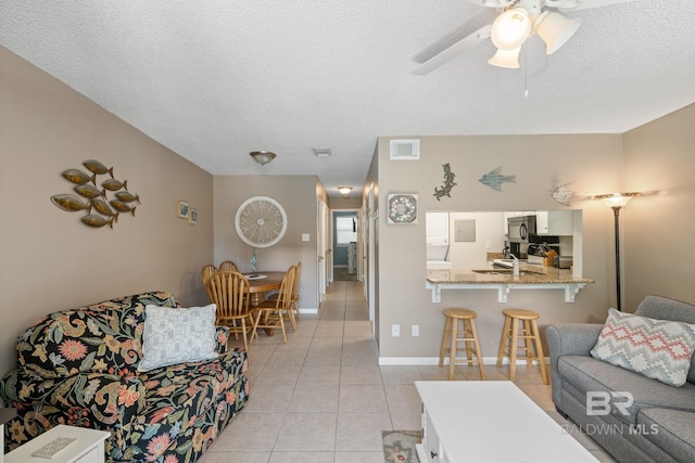 tiled living room featuring ceiling fan, sink, and a textured ceiling