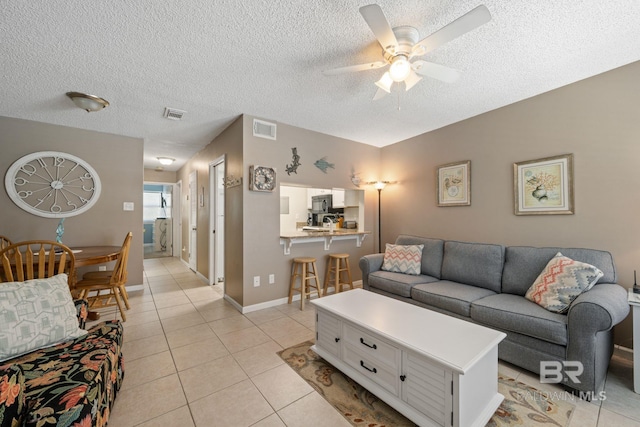 living room with a textured ceiling, light tile patterned floors, and ceiling fan