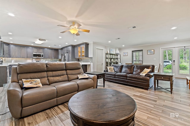 living room featuring ornamental molding, french doors, ceiling fan, and light wood-type flooring