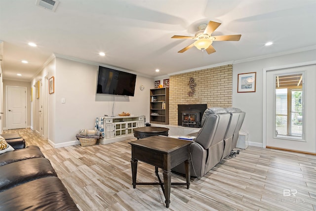 living room featuring ornamental molding, light wood-type flooring, ceiling fan, and a fireplace