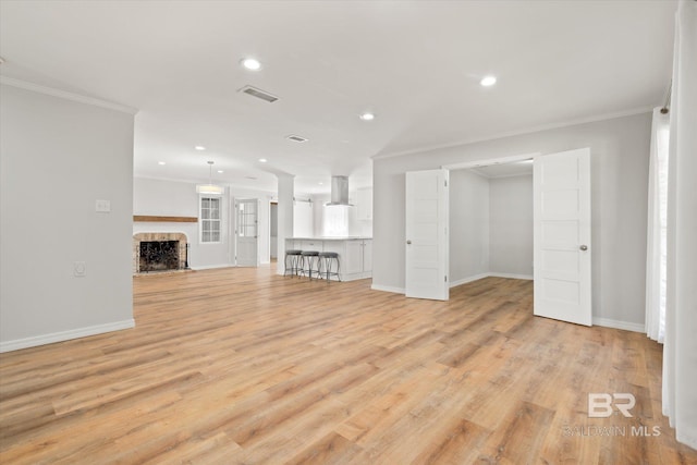 unfurnished living room with light wood finished floors, visible vents, crown molding, recessed lighting, and a fireplace