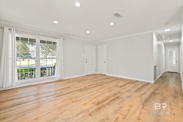 unfurnished room with light wood finished floors, visible vents, attic access, and ornamental molding