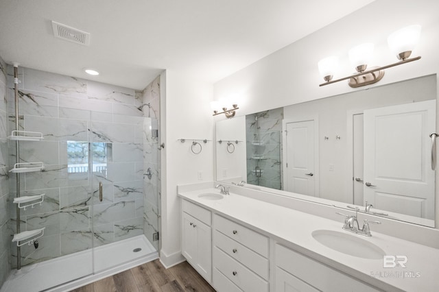 bathroom featuring a marble finish shower, wood finished floors, a sink, and visible vents