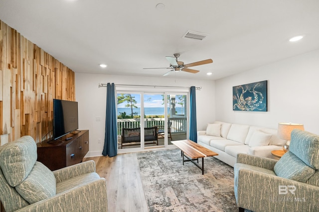 living area with wooden walls, visible vents, a ceiling fan, light wood-style floors, and recessed lighting