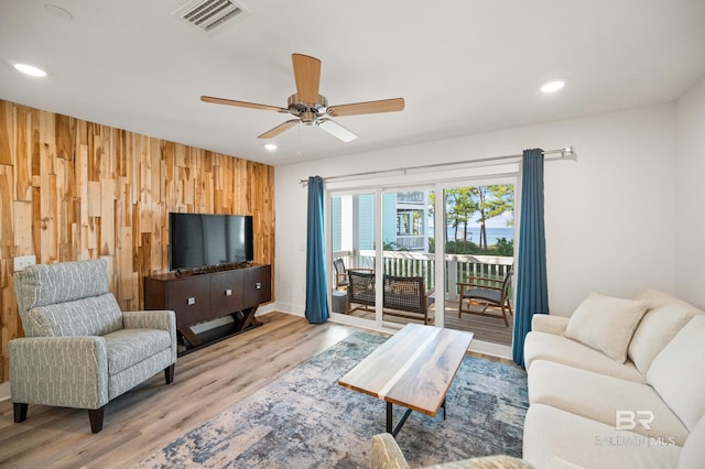 living room with recessed lighting, wood finished floors, visible vents, and wooden walls