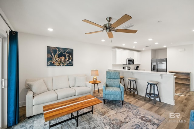 living area with recessed lighting, visible vents, ceiling fan, and wood finished floors