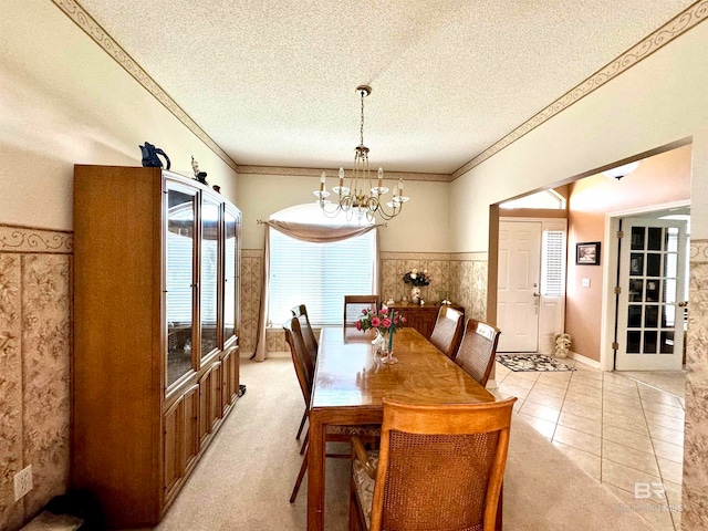 carpeted dining space featuring a textured ceiling, crown molding, and a notable chandelier