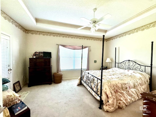 bedroom with a textured ceiling, carpet floors, a raised ceiling, crown molding, and ceiling fan