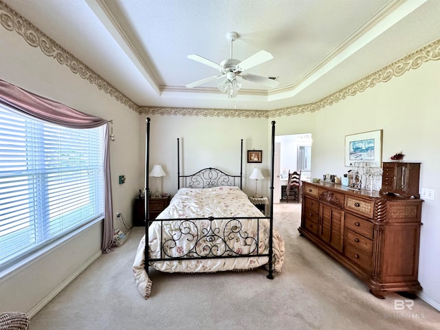 carpeted bedroom featuring ceiling fan, a tray ceiling, and crown molding