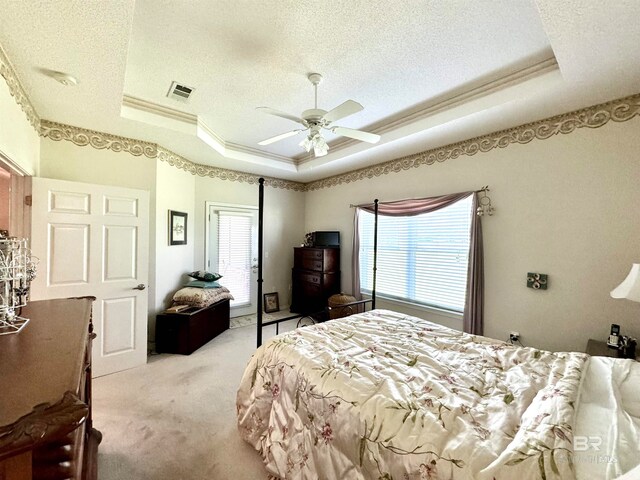 bedroom with ceiling fan, a tray ceiling, and multiple windows