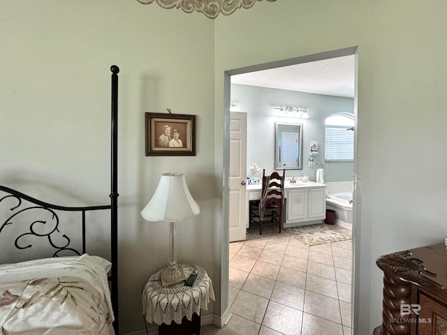 tiled bedroom with connected bathroom, a textured ceiling, and sink