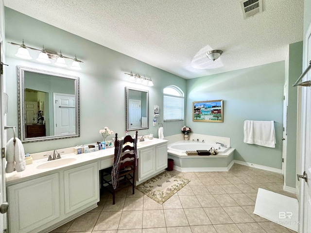 bathroom with tile patterned flooring, a tub to relax in, a textured ceiling, and vanity