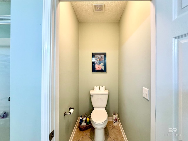 bathroom with a textured ceiling, tile patterned flooring, and toilet