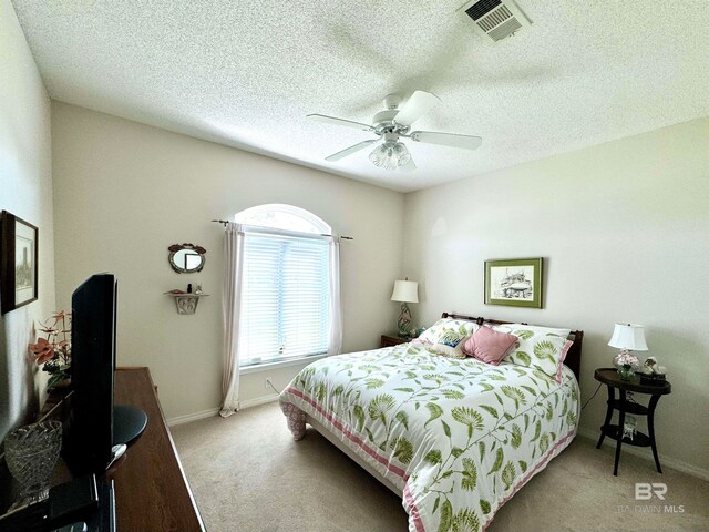 bedroom with a textured ceiling, light carpet, and ceiling fan