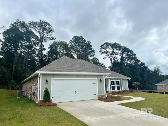 view of front of home with a front yard, a garage, and central AC