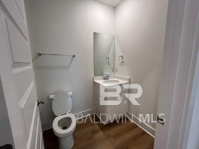 bathroom with toilet, vanity, and wood-type flooring