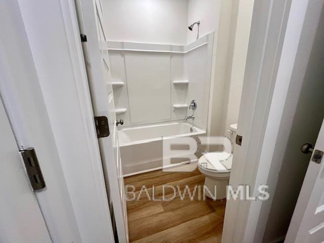 bathroom with toilet, washtub / shower combination, and wood-type flooring