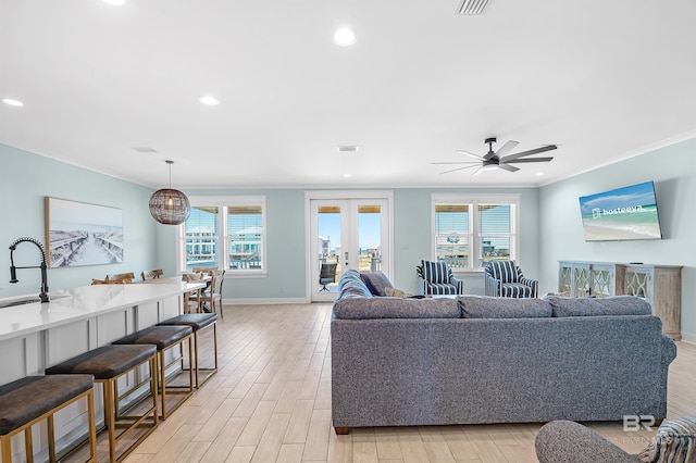 1337 W Lagoon Ave, Gulf Shores, AL 36542 - living room with light wood-type flooring, ornamental molding, and a healthy amount of sunlight