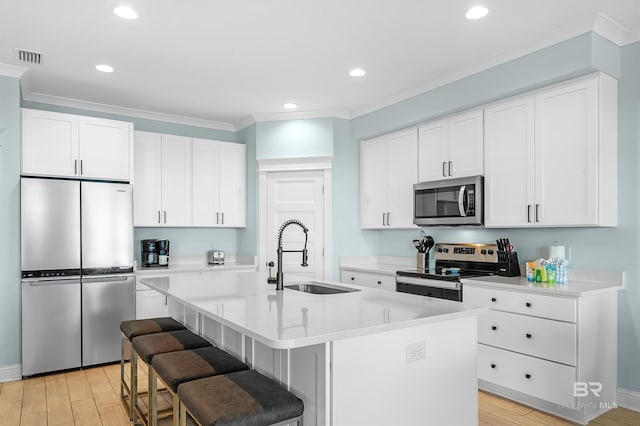 1337 W Lagoon Ave, Gulf Shores, AL 36542 - kitchen featuring crown molding, a center island with sink, appliances with stainless steel finishes, a sink, and light wood-style floors