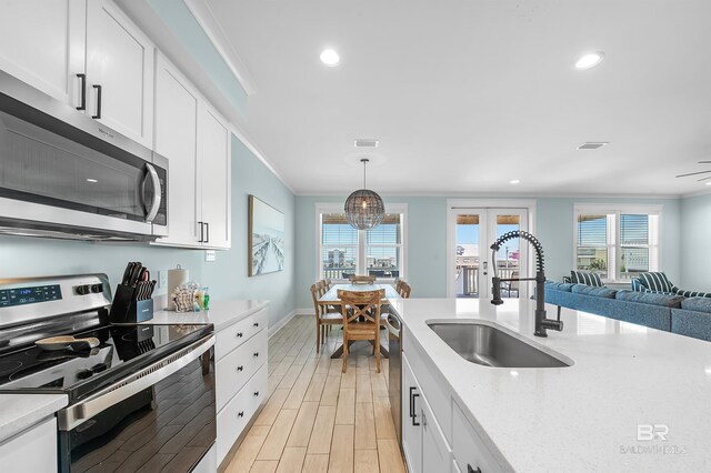 1337 W Lagoon Ave, Gulf Shores, AL 36542 - kitchen featuring a sink, white cabinetry, appliances with stainless steel finishes, light wood-type flooring, and ornamental molding