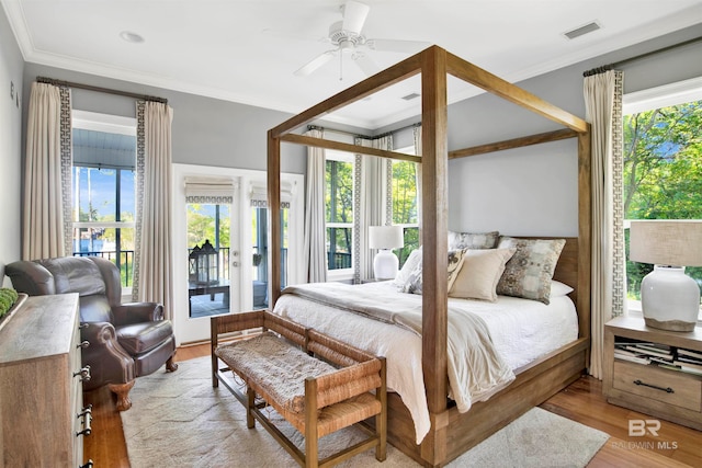 bedroom featuring ceiling fan, light hardwood / wood-style floors, ornamental molding, and multiple windows