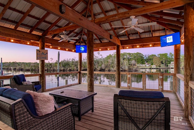 deck at dusk featuring a gazebo, ceiling fan, and an outdoor living space with a fire pit