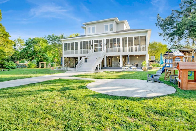 rear view of property with a lawn, a sunroom, a playground, and a patio