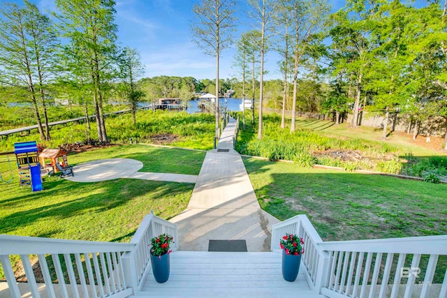 surrounding community with a playground, a water view, and a lawn