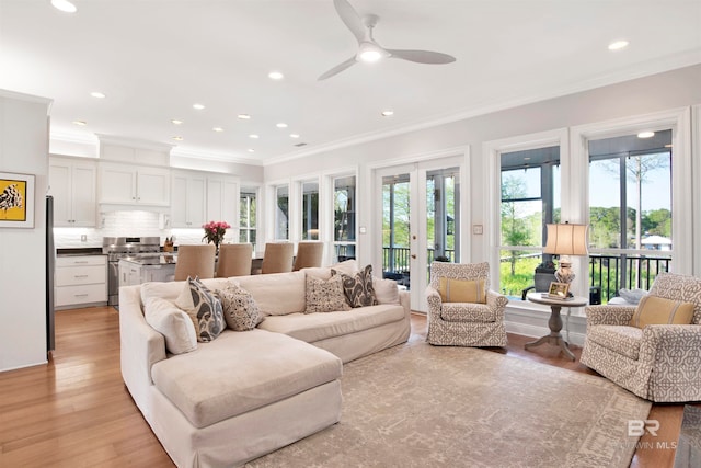 living room featuring light wood-type flooring, plenty of natural light, crown molding, and ceiling fan