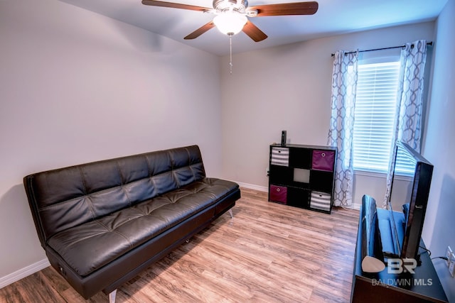 sitting room with baseboards, wood finished floors, and a ceiling fan