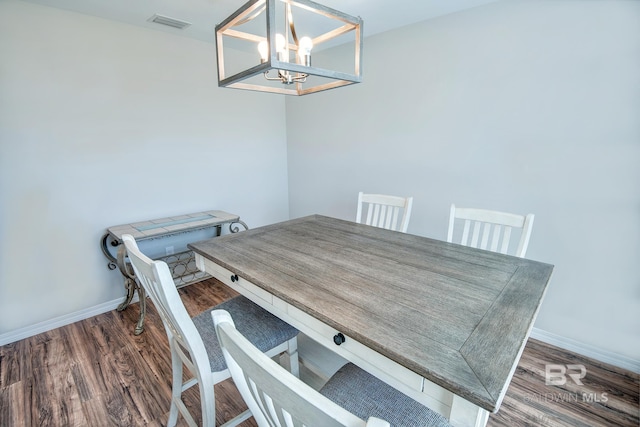 unfurnished dining area with baseboards, visible vents, wood finished floors, and an inviting chandelier
